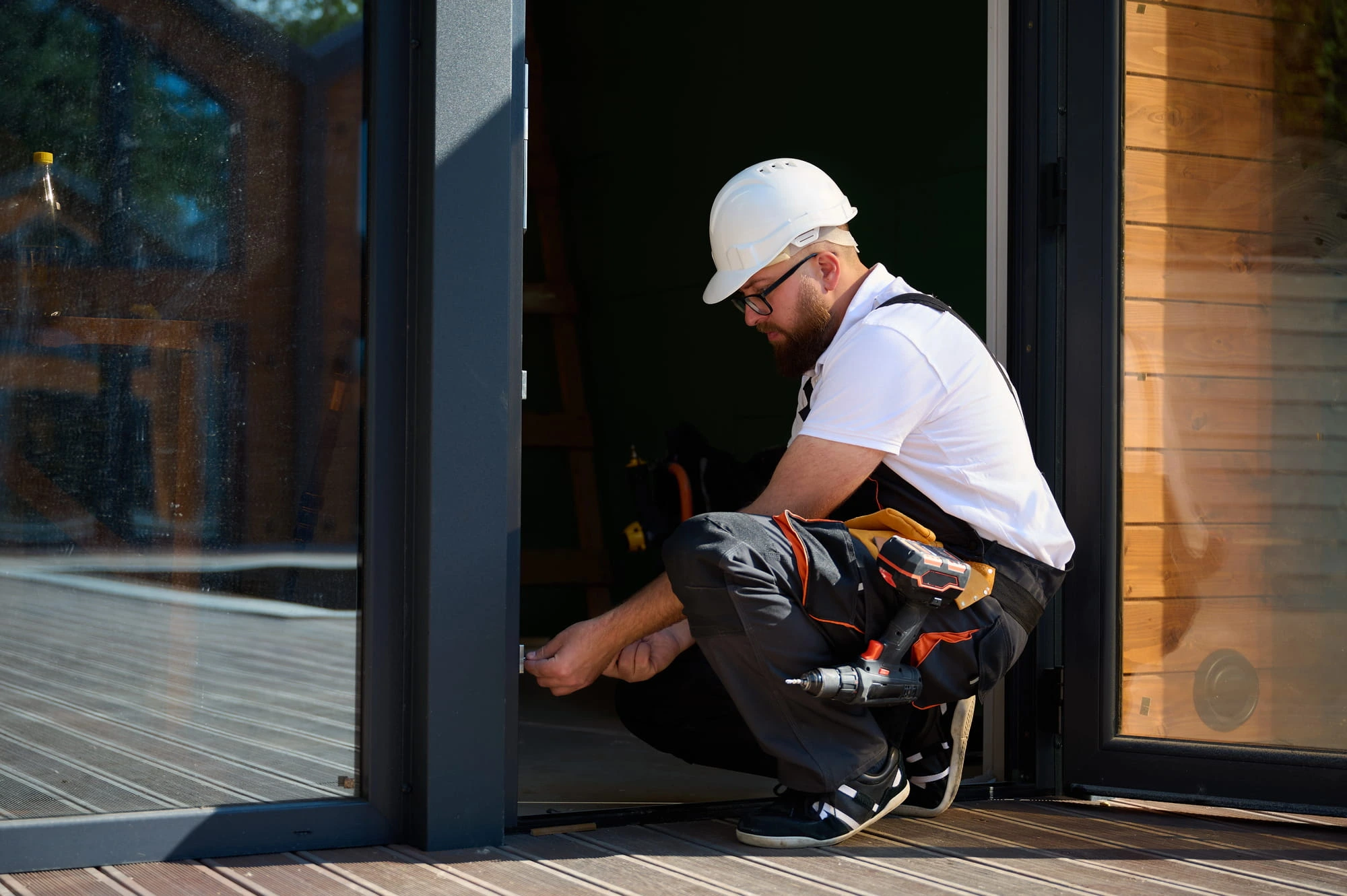Technician crouched at the base of a storefront door setting the bottom pivot and floor alignment